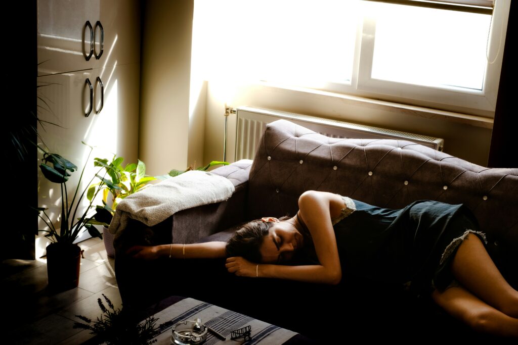 Exhausted girl laying on the couch feeling tired and unmotivated